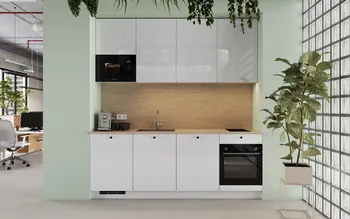 Moderne weiße Einbauküche in mintgrüner Nische mit Holzrückwand, Einbaumikrowelle, Induktionskochfeld, Backofen und Spüle; Kaffeemaschine links, große Zimmerpflanze und Glasbausteinwand rechts; Blick ins offene Büro.